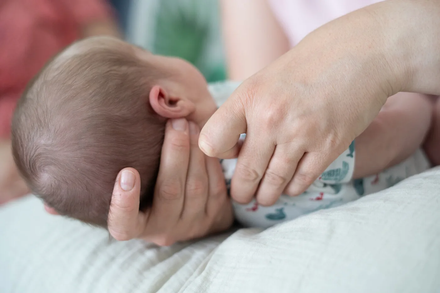 Gros plan sur les mains d'un nourrisson lors d'une séance d'ostéopathie périnatale